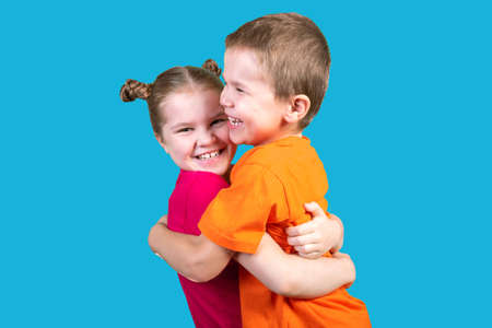 Brother and sister are hugging in isolation, on a blue background.の写真素材