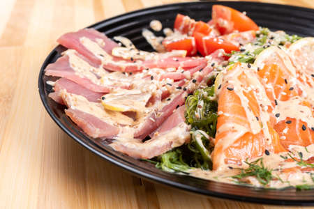 Salmon and tuna sashimi in a salad with herbs. For any purpose.