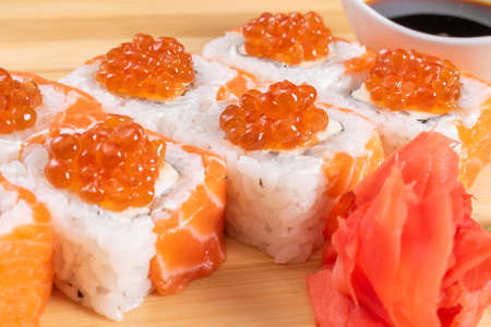 Sushi, with curd cheese, salmon and caviar. On the plank. On a red background. For any purpose.