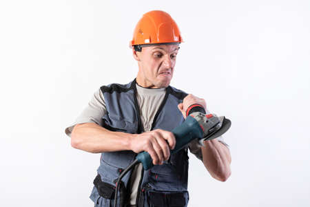 Builder with angle grinder, in a helmet, with a funny expression on his face. For any purpose.の写真素材
