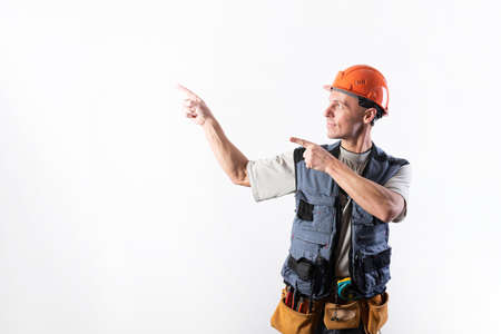The builder points to the left. Offers with index fingers. In work clothes and hard hat. For any purpose.の写真素材