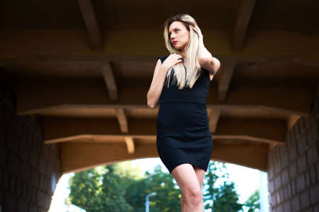 Attractive blonde in a black dress. Under the bridge. From below. For any purpose.の写真素材
