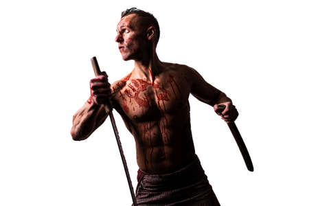 An athletic man, in blood, with a Japanese sword, strikes. Isolated on a white background.の写真素材