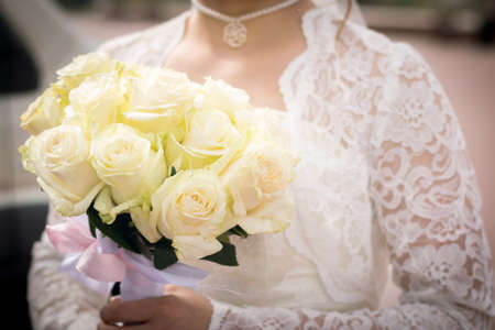 Bridal bouquet of white roses in the hands. For any purpose.
