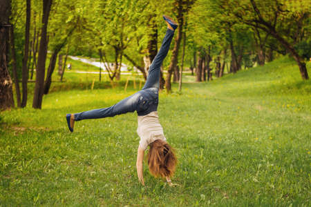 Girl makes an acrobatic wheel. On the grass. For any purpose.