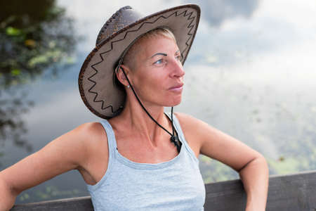 A woman in a cowboy hat, in nature. Near water. For any purpose.の写真素材
