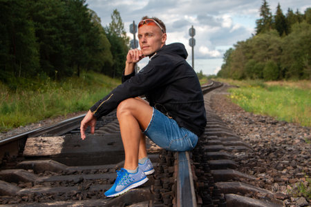 The man is sitting on the rails and thinking. For any purpose.