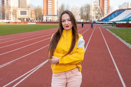 Girl, in ordinary clothes, on a treadmill of a stadium.の写真素材