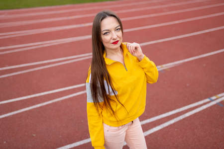 Girl, in ordinary clothes, on a treadmill of a stadium.の写真素材
