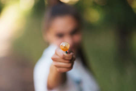 The girl shows the candy on a stick in the frame. For any purpose.の写真素材