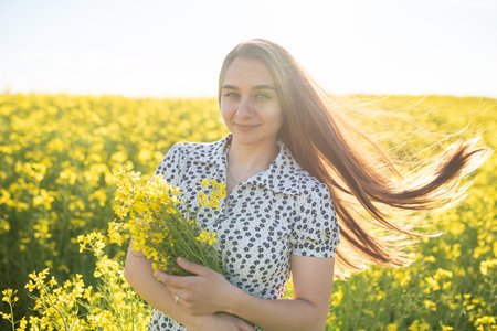 Beautiful girl in a rapeseed field, with her hair in the sun. High quality photo