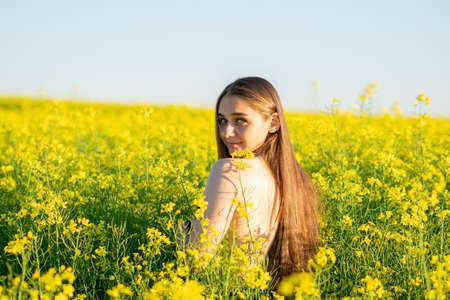 Beautiful girl in a rapeseed field, with an open shoulder. High quality photoの写真素材