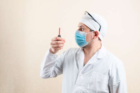 Doctor in mask and glasses shows an enema. High quality photo