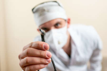 Doctor ENT, wearing a mask and glasses, with a device in his hands. High quality photoの写真素材