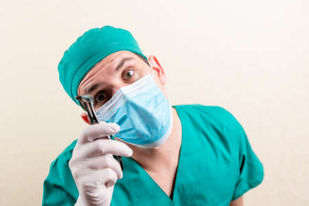 Doctor ENT, wearing a mask and glasses, with a device in his hands. High quality photoの写真素材