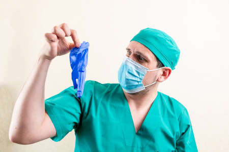 A doctor in a mask and a cap, plays with gloves.の写真素材