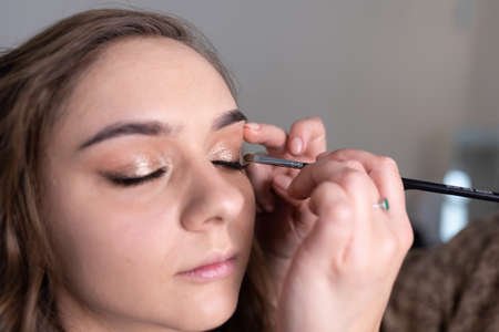 Make-up artist applies eyeliner to the girl's upper eyelid with a brush. high quality photoの写真素材