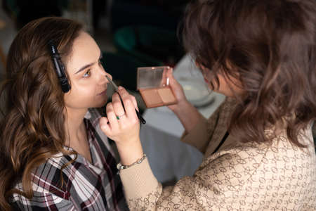 Makeup artist applying eyeshadow to girls upper eyelid with a brush