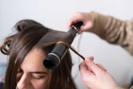 The stylist curls the girl's hair with a curling iron. high quality photo