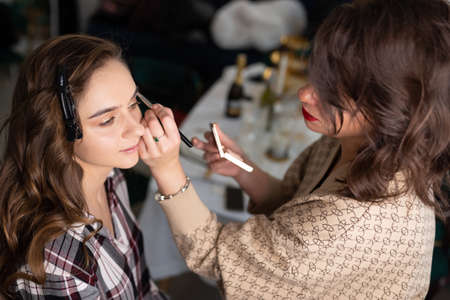 Makeup artist applying eyeshadow to girl's upper eyelid with a brush. high quality photoの写真素材