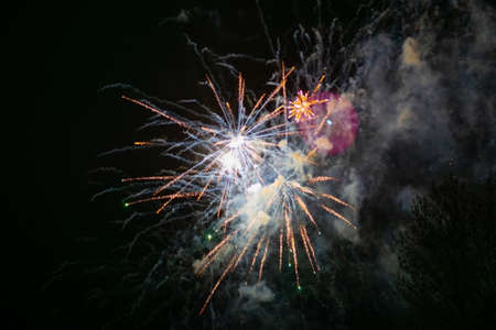 Two bright explosions of fireworks, yellow, with haze, against the background of the night sky. high...