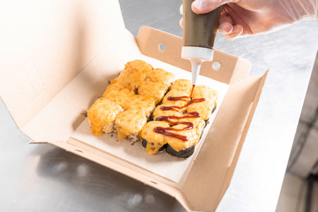 A set of baked sushi with a cheese cap, in a box, poured with sauce. high quality photoの写真素材