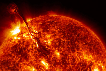 Solar flare erupting from the sun's surface against dark space backgroundの写真素材