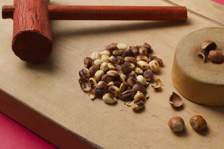 Hazelnuts on wooden background with hammer and anvil