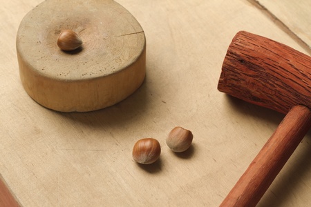 Hazelnuts, hammer and anvil on wooden background