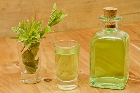 Peppermint plant, liqueur bottle and shot on wooden background の写真素材