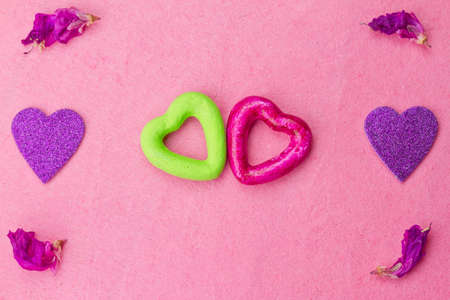 Green and purple hearts on pink background with rose petals