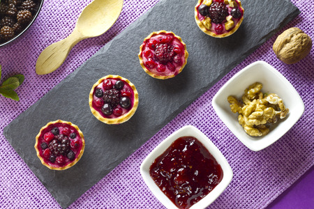 Autumn fruits cakes on a slate plate and ingredients on purple backgroundの写真素材