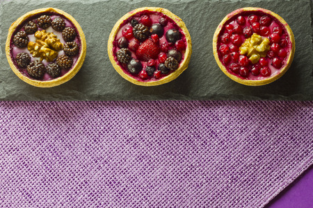 Three autumn fruits cakes on a slate plate on purple backgroundの写真素材