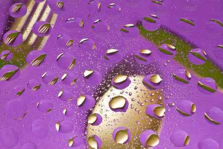 Golden fork knife and spoon and drops reflection on purple backgroundの写真素材