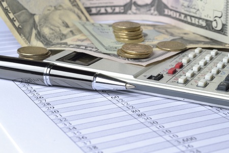 Business background with table, coins, calculator and pen.