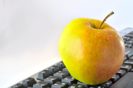 Apple and keyboard on grey background.
