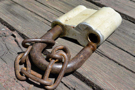 Rusty lock with chain on wooden background.の写真素材