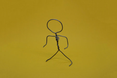 Metal man made of wire stands on the yellow backgroundの写真素材