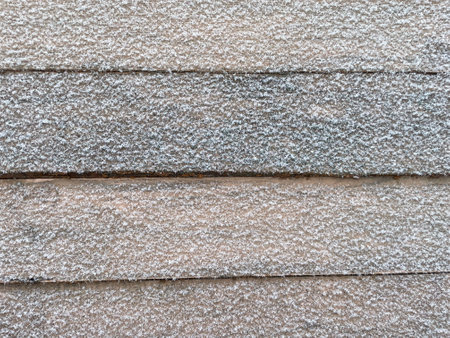 A detailed winter photograph featuring painted wooden planks topped with a fresh layer of snow.の写真素材