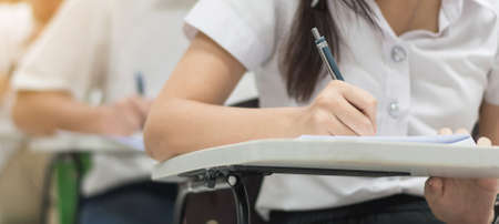 School exam, education concept with student taking examination or admission test writing answer in...