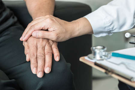 Geriatric doctor (geriatrician) consulting and diagnostic examining elderly senior adult patient (older person) on aging and mental health care in medical clinic office or hospital examination roomの写真素材