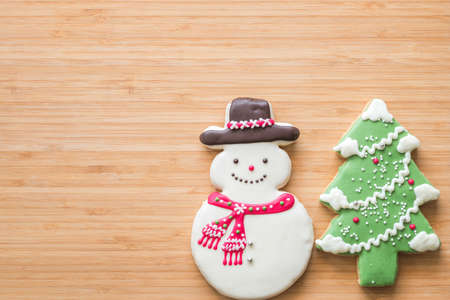 Christmas cookies, snowman, X'mas tree, gingerbread flat lay on wooden cutting board background top view for Xmas party holiday food design decoration backdrop with copy spaceの写真素材