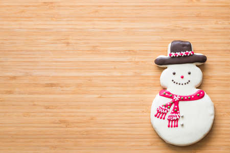 Christmas snowman cookies flat lay on wooden cutting board background top view for Xmas party holiday food design decoration backdrop with copy spaceの写真素材