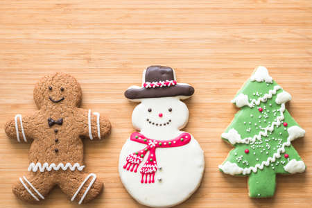 Christmas cookies, snowman, X'mas tree, gingerbread flat lay on wooden cutting board background top view for Xmas party holiday food design decoration backdrop with copy spaceの写真素材