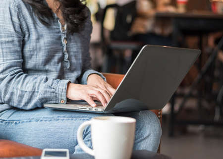 Digital lifestyle blogger (blog writer) or business woman person using computer and mobile smart device working on internet technology in coffee shop for social media communicationの写真素材