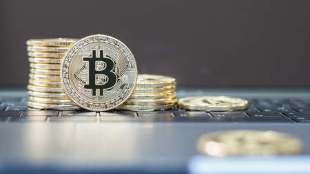 Bitcoin cryptocurrency on keyboard with gold stack coins of virtual digital currency for fintech financial banking business and world stock exchange investment via internet online computer technology conceptの写真素材