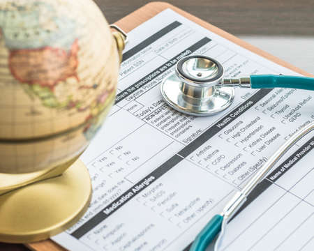 Patient's healthcare record clip pad with doctor's stethoscope on work tableの写真素材