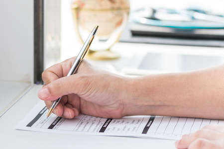 Physician doctor writing on medical health care record, patients discharge, or prescription form paperwork in hospital clinicの写真素材