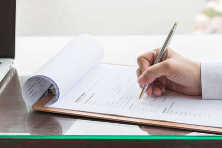 Applicant filling in company application form document applying for job, or registering claim for health insuranceの写真素材