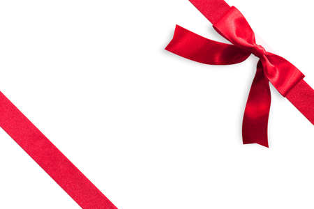 Red bow satin ribbon band stripe fabric on corner (isolated on white background with clipping path) for Christmas holiday gift box present wrap design decoration ornament elementの写真素材